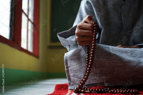 Hand of Muslim praying using prayer beads photo