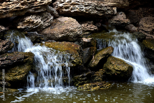 Small waterfalls pour from a stone pile in the park
