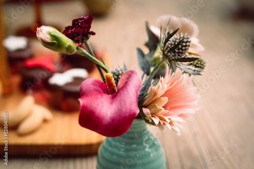 Quadro em tela Rosquinhas com sequilhos e doces de chocolate na mesa posta com flores e bolas d