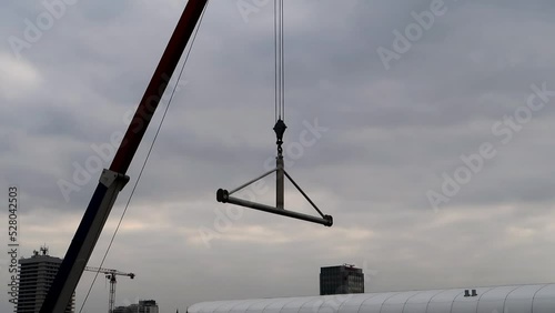 Kranausleger mit Himmel als Hintergrund, Kranhaken schwingt im Wind photo