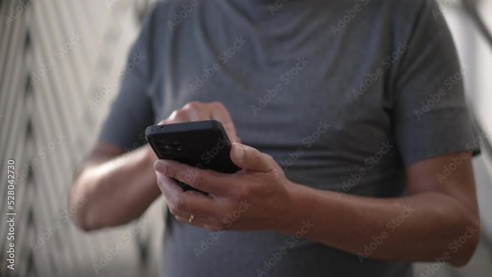 Person using cellphone standing outdoors in city street sidewalk. Closeup hands holding smartphone device texting message Person using cellphone standing outdoors in city street sidewalk. Closeup hands holding smartphone device texting message