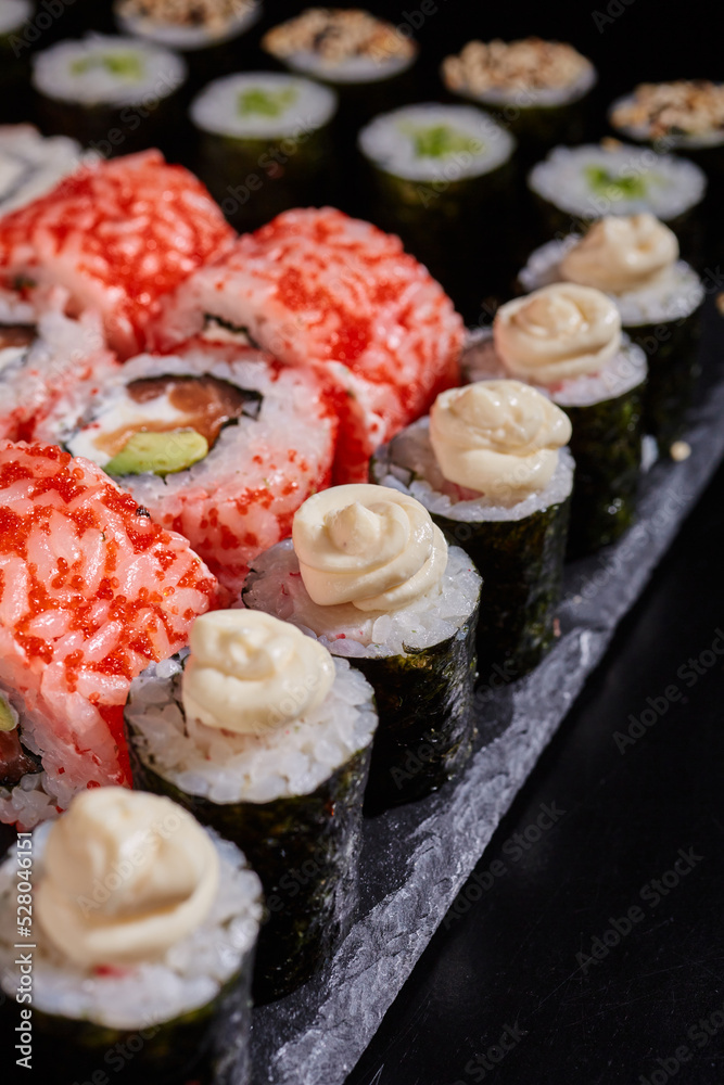 Close up of maki rolls with cream cheese lying on a black flat plate. Close up of maki rolls with cream cheese lying on a black flat plate.