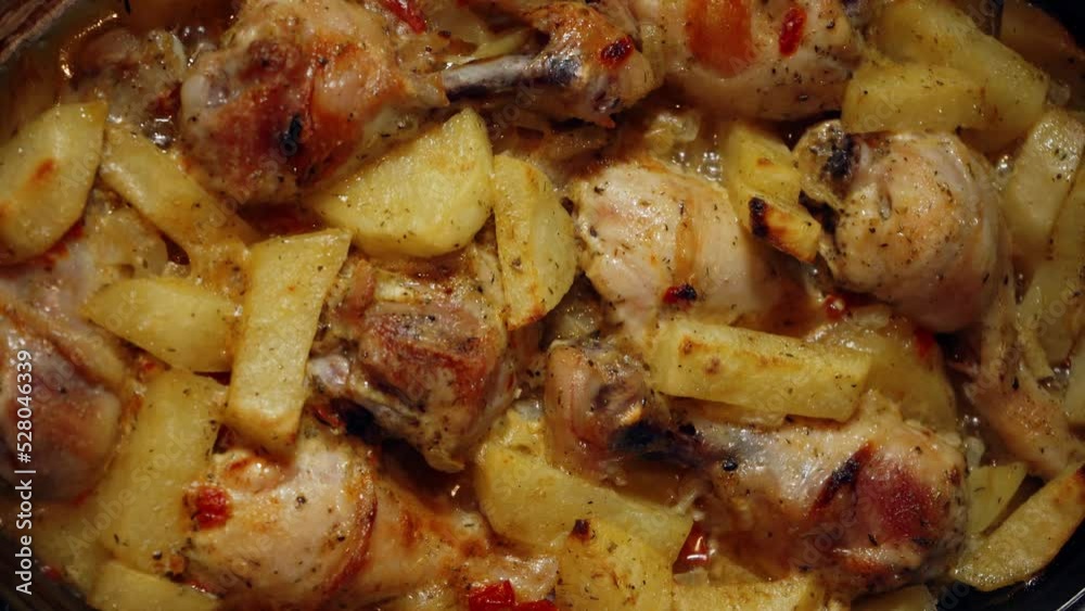 Baked hot potatoes with chicken legs only from the oven. A dish cooked at home. Hot fat and juice heats up, squirts and bubbles on a baking sheet Baked hot potatoes with chicken legs only from the oven. A dish cooked at home. Hot fat and juice heats up, squirts and bubbles on a baking sheet