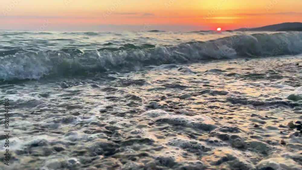 Beautiful sunset on the seashore on a bright sunny day. The waves break beautifully on the pebbles on the shore.Reflection of sunlight on the water surface. Amazing beauty of nature, sunset landscape Beautiful sunset on the seashore on a bright sunny day. The waves break beautifully on the pebbles on the shore.Reflection of sunlight on the water surface. Amazing beauty of nature, sunset landscape