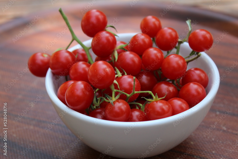 Some tiny cherry tomatoes and green peppers in white plates on wooden concept. Some tiny cherry tomatoes and green peppers in white plates on wooden concept.