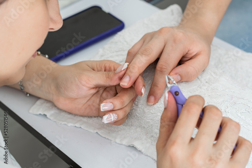detail shot of the hands of a latin manicurist performing the correct cleaning of the nails with a pair of pliers or cuticle scissors, carefully observing where the imperfections are.