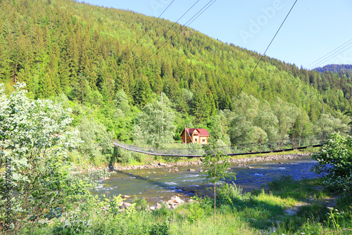 Landscape with suspension bridge and River Black Cheremosh in village of Krivorivnya, Ukraine	
 photo