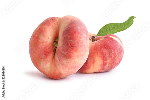 Two flat peaches with leaf  isolated on white