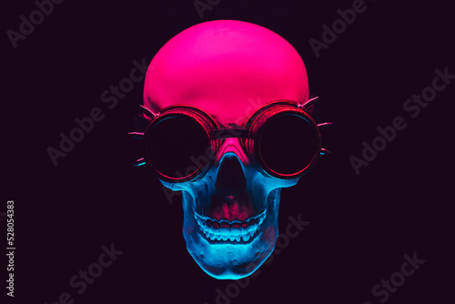 human skull in steampunk glasses with colored neon light on a black background