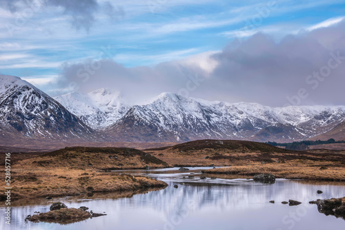 Majestic Winter panorama landscape image of mountain range and peaks viewed from Loch Ba in Scottish Highlands with dramatic clouds overhead © veneratio
