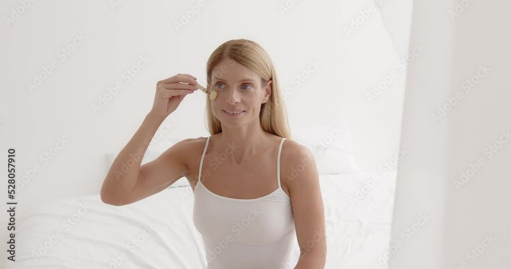 Blonde mature woman enjoying face massage with jade roller Blonde mature woman enjoying face massage with jade roller