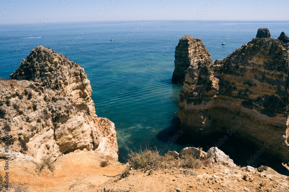 NATURE WITH THE SEA ON THE HORIZON ON A SUNNY DAY WITH BLUE SKY IN THE ALGARVE BOATS IN THE AREA AND LARGE CLIFFS