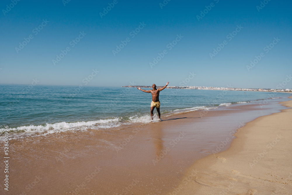 GUY  WALKING ON THE BEACH ON HIS SUNNY VACATION VERY HAPPY