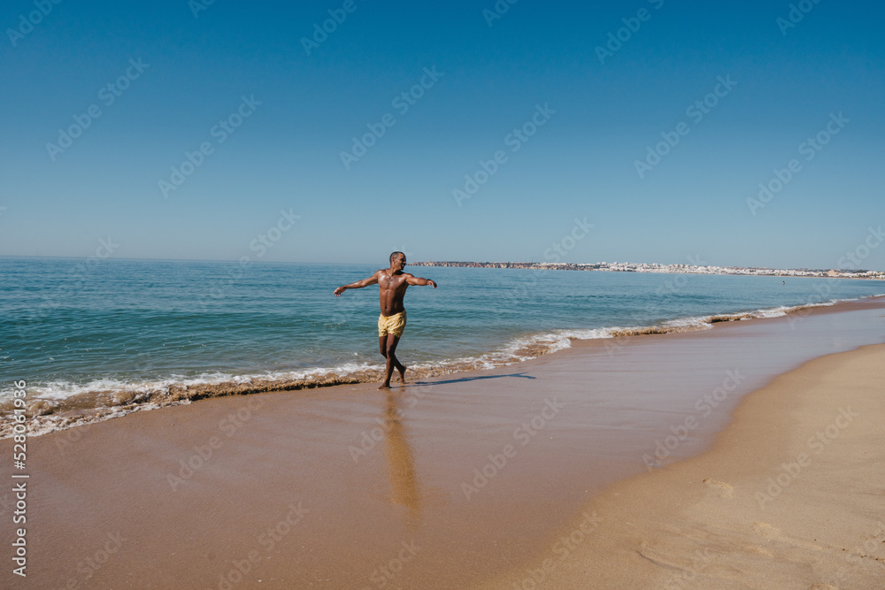 AFRICAN-AMERICAN BOY WALKING ON THE BEACH ON HIS SUNNY VACATION VERY HAPPY AFRICAN-AMERICAN BOY WALKING ON THE BEACH ON HIS SUNNY VACATION VERY HAPPY