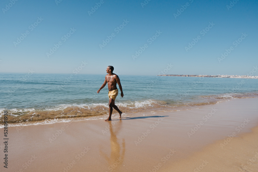 AFRICAN-AMERICAN BOY WALKING ON THE BEACH ON HIS SUNNY VACATION AFRICAN-AMERICAN BOY WALKING ON THE BEACH ON HIS SUNNY VACATION