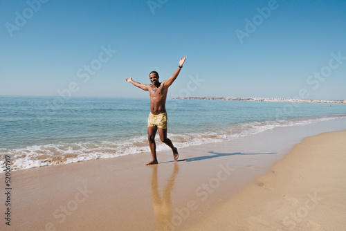 GUY WALKING ON THE BEACH ON HIS SUNNY VACATION VERY HAPPY