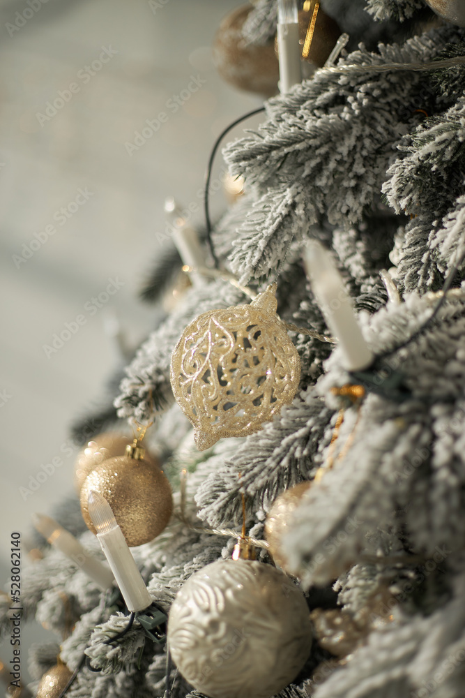 artificial lush cast snowy Christmas tree spruce decorated with white golden balls candles lights garland close up in white interior artificial lush cast snowy Christmas tree spruce decorated with white golden balls candles lights garland close up in white interior