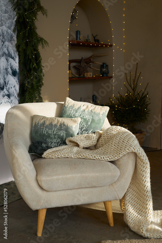 cozy corner in the New Year's room, a comfortable white soft chair with pillows and plaid bedspread photo