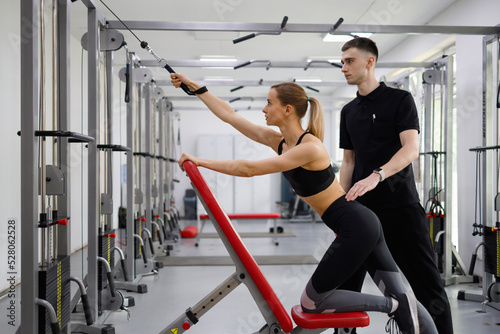 Young fitness woman training with personal trainer man in the gym
