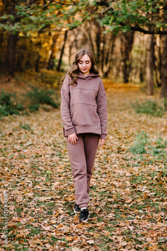 Young woman in hoodie sweater in an autumn park. Sunny weather. Fall season.