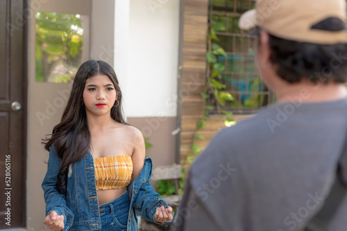 A beautiful teenager in a denim outfit and loose curls gestures her hands as she tries to explain her frustrations to her dad. photo