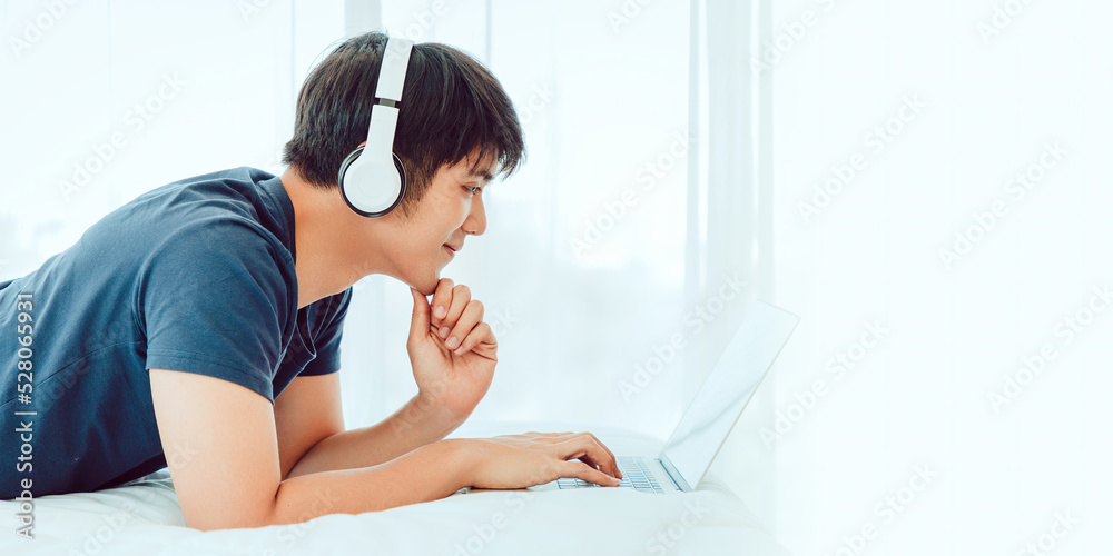 Happy man using Laptop computer and checking good News in the Bedroom. COPY SPACE. Trading. Watching Movie. WORK FROM HOME Concept. Happy man using Laptop computer and checking good News in the Bedroom. COPY SPACE. Trading. Watching Movie. WORK FROM HOME Concept.