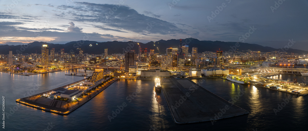 Panoramic view of piers and harbor against city skyline lights at sunset