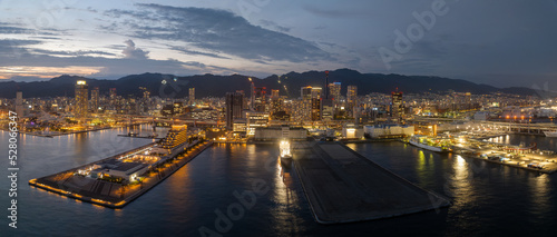 Panoramic view of piers and harbor against city skyline lights at sunset