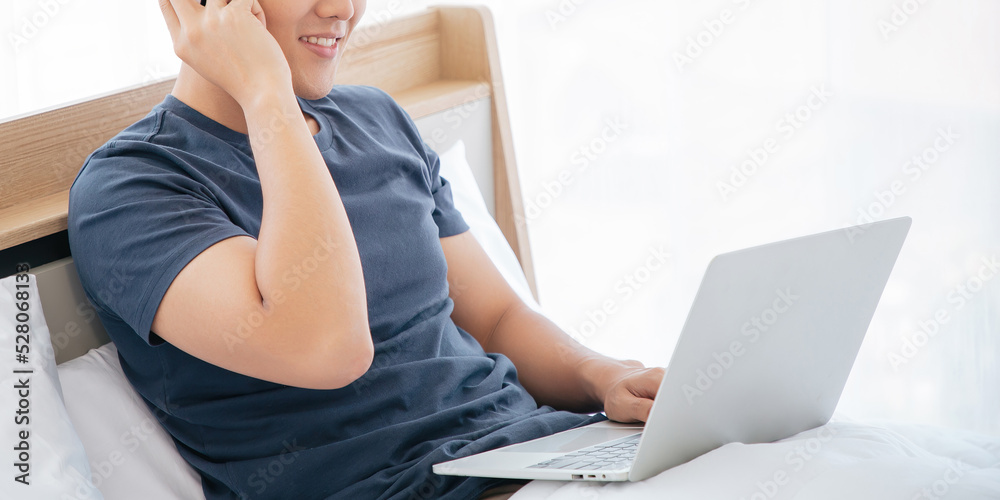 Naklejka premium Unrecognizable Happy man using Laptop computer and checking good News in the Bedroom. COPY SPACE. Trading. Watching Movie. WORK FROM HOME WFH Concept.