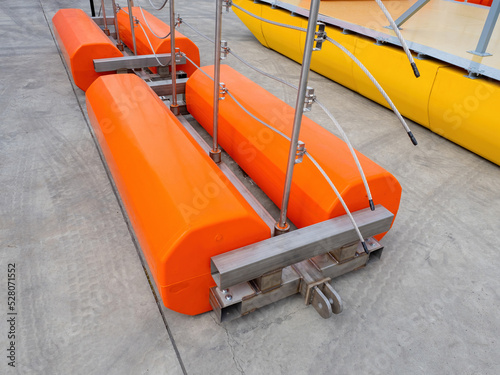 Pontoons with electric cables. Device for laying electrical wires above water. Orange pontoons around metal frame. Equipment for electrification. Floating pontoons for laying electric tracks © Grispb