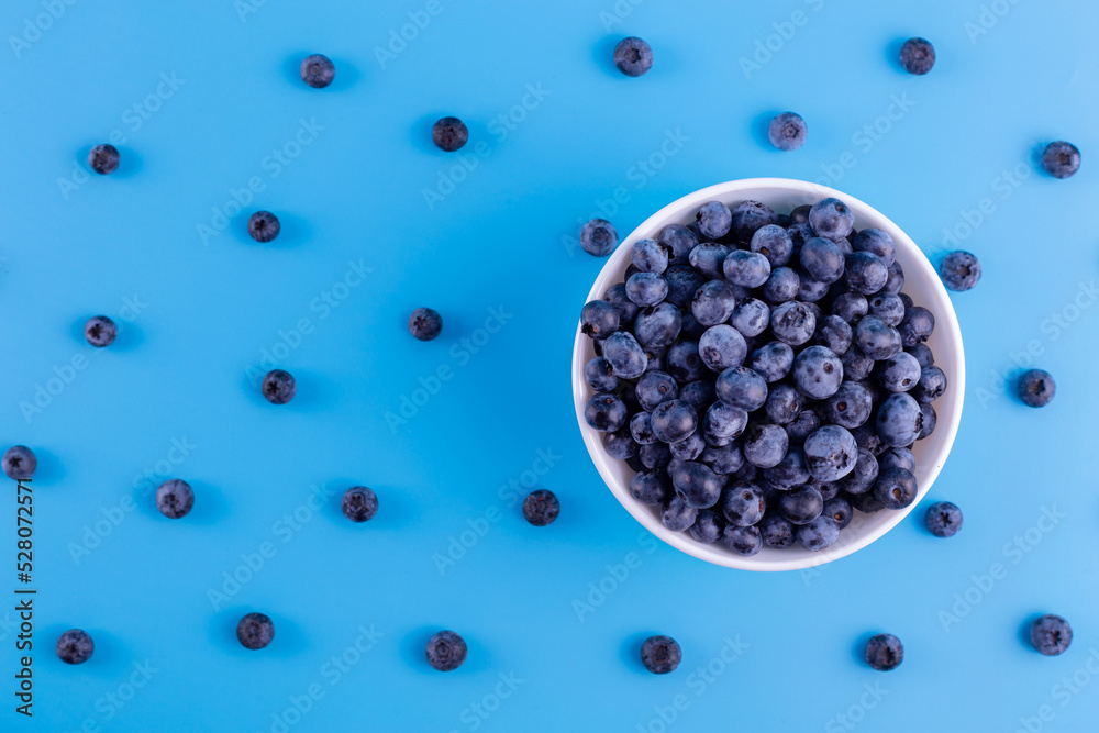 Fresh blueberries in white bowl on blue background. Flat lay, top view..Vegan and vegetarian concept. Summer healthy food. Fresh blueberries in white bowl on blue background. Flat lay, top view..Vegan and vegetarian concept. Summer healthy food.