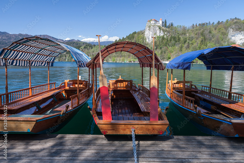 Traditional wooden row boats on famous Lake Bled with Bled Castle in background, Slovenia, Europe, Spring