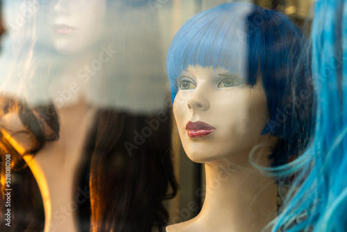 Female mannequin heads with wigs, behind a wig shop window © MiguelAngel
