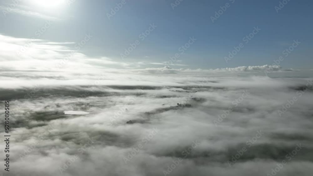 Flying above clouds over hills. above fog on a farm landscape below. mist covering the mountains in the country Flying above clouds over hills. above fog on a farm landscape below. mist covering the mountains in the country