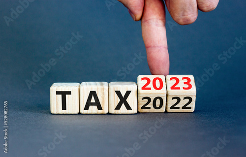 2023 tax new year symbol. Businessman turns a wooden cube and changes words Tax 2022 to Tax 2023. Beautiful grey table grey background, copy space. Business 2023 tax new year concept.