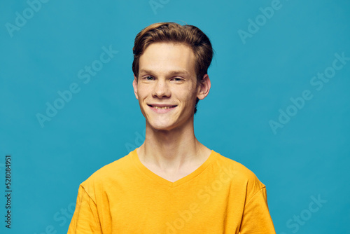 portrait of a cute guy on a blue background in a yellow T-shirt