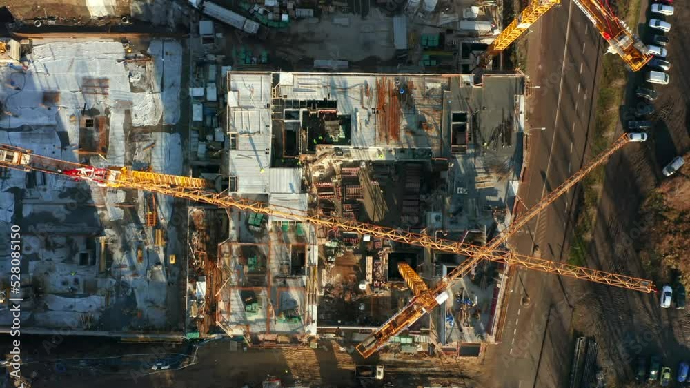 Drone shot from top to bottom on a construction site with cranes and construction equipment. Construction of new housing in the new quarter of the old town