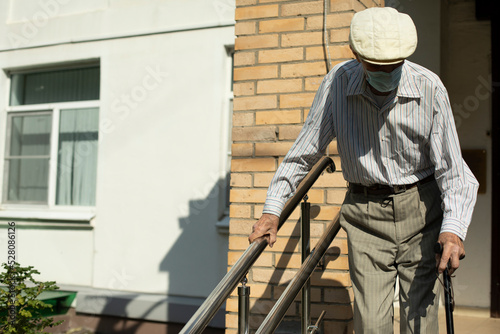 The old man goes down the ramp for the disabled. The pensioner leaves the hospital.