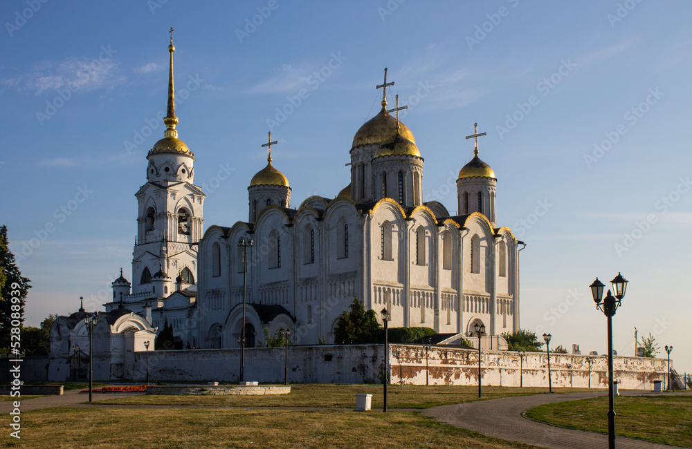 Vladimir, Russia - August, 17, 2022: the ancient white-stone Assumption Cathedral with shining golden domes on a bright sunny summer day