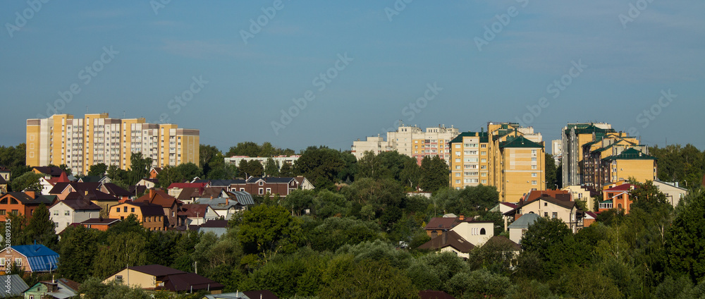 Panoramic top view of the city of Vladimir in Russia with old wooden houses and modern high-rise buildings among the lush green foliage of trees on a sunny summer day