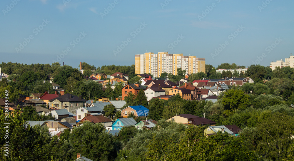 Obraz premium Panoramic top view of the city of Vladimir in Russia with old wooden houses and modern high-rise buildings among the lush green foliage of trees on a sunny summer day