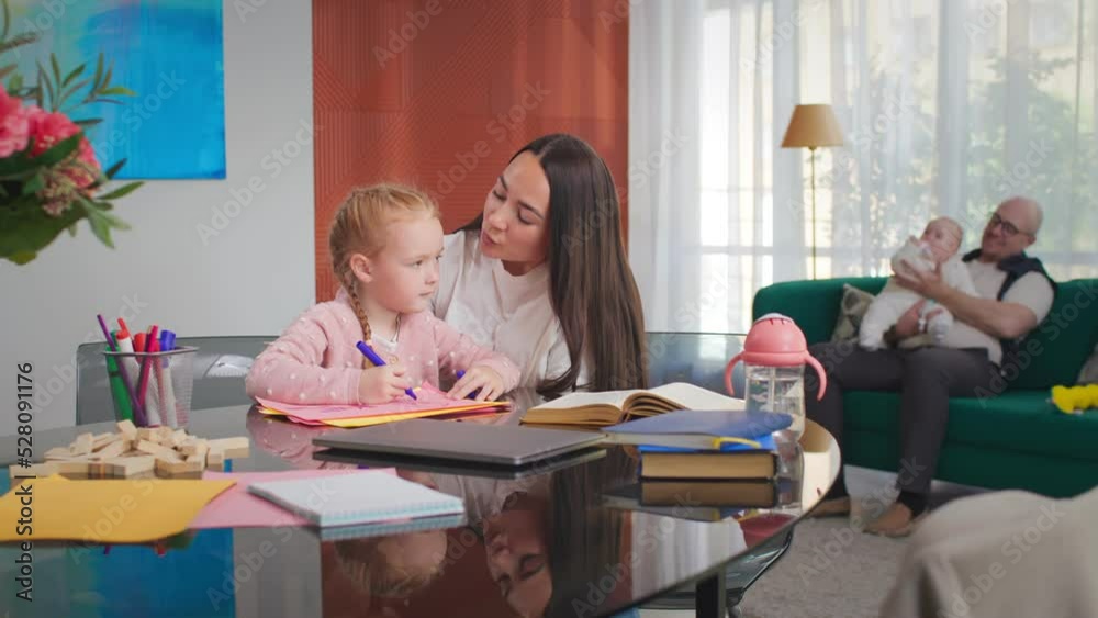 Mother and little daughter doing homework together and hugging Mother and little daughter doing homework together and hugging
