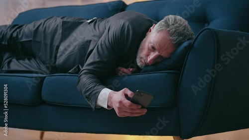 Wallpaper Mural Tired businessman lying on sofa, reading news about company bankruptcy on phone Torontodigital.ca