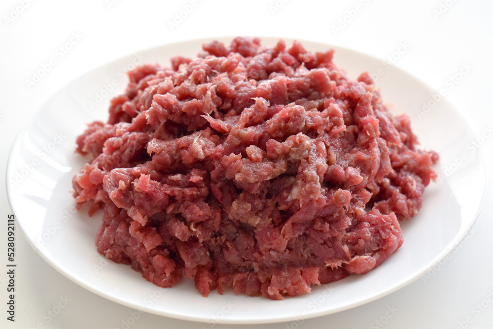 Raw minced beef or ground beef on a white plate. Raw minced beef or ground beef on a white plate.