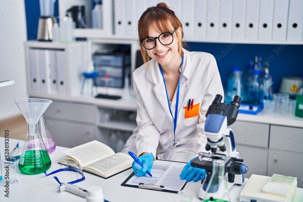 Young woman scientist write on document at laboratory Young woman scientist write on document at laboratory