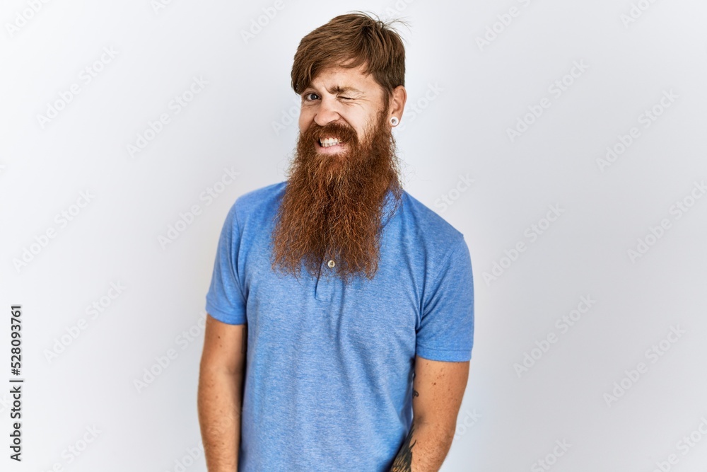 Caucasian man with long bear standing over isolated background winking looking at the camera with sexy expression, cheerful and happy face. Caucasian man with long bear standing over isolated background winking looking at the camera with sexy expression, cheerful and happy face.