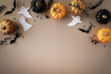 Halloween holiday frame with party decorations of pumpkins, bats, ghosts, spiders on golden background top view. Happy halloween greeting card in flat lay style.
