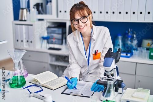 Young woman scientist write on document at laboratory