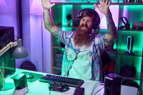 Young redhead man streamer stressed using computer at gaming room