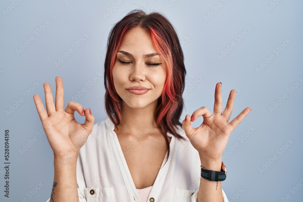 Young caucasian woman wearing casual white shirt over isolated background relaxed and smiling with eyes closed doing meditation gesture with fingers. yoga concept. Young caucasian woman wearing casual white shirt over isolated background relaxed and smiling with eyes closed doing meditation gesture with fingers. yoga concept.